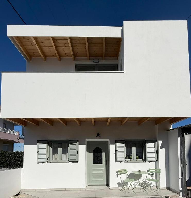 a white house with a green door and chairs at Spitaki in Kremasti