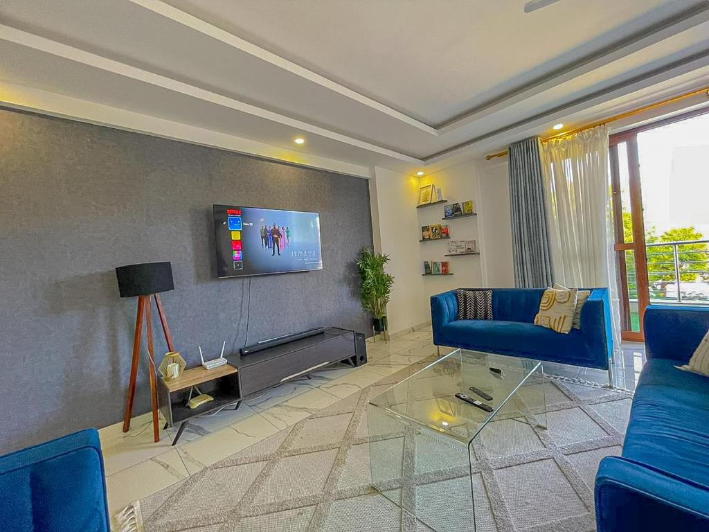 a living room with a blue couch and a tv at Aqua Epic Residence in Mombasa
