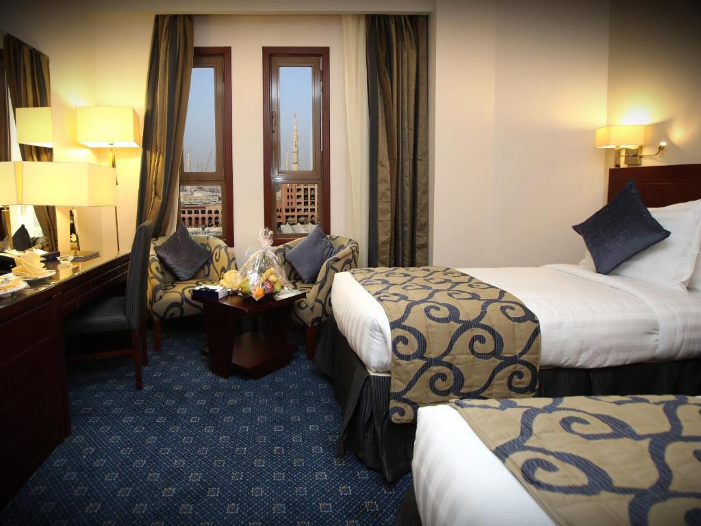 a hotel room with two beds and a desk at Al Rawda Al Aqeeq Hotel in Medina