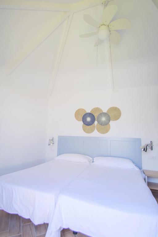 a bedroom with a bed with white sheets and a ceiling at Los Cardones Boutique Village in Playa de las Americas