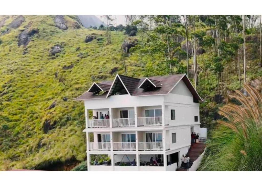 a large white house with a hill in the background at Clouds end Resorts Munnar in Jāmb