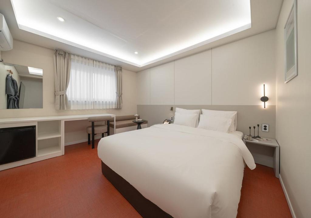 a bedroom with a large white bed and a television at No 25 Iksan Station Branch in Iksan