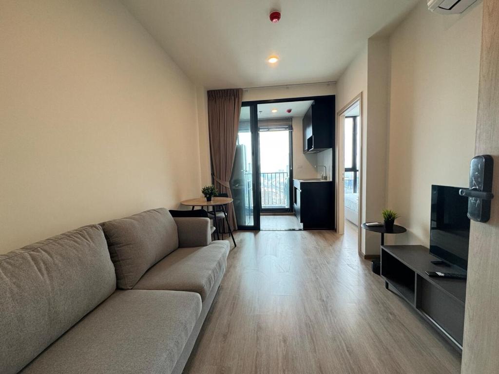 a living room with a couch and a television at NUE District Rama 9 Condo in Bangkok