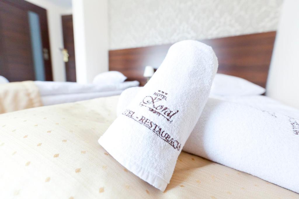 a towel on a bed with a sock on it at Hotel - Restauracja Koral in Wieliczka