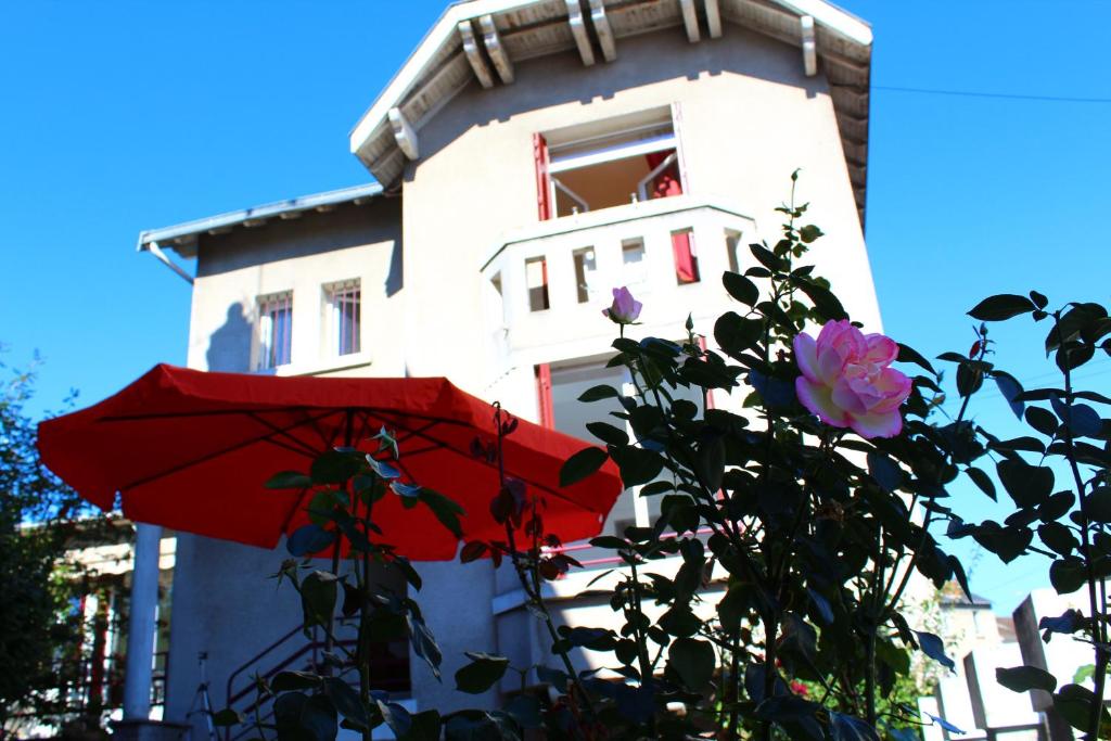 un parapluie rouge et des fleurs devant un bâtiment dans l'établissement Cottage de Noëlle, à Limoges