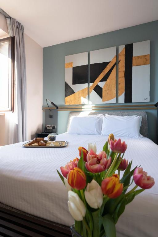a bedroom with a bed with a vase of flowers at Le Funi Hotel in Bergamo