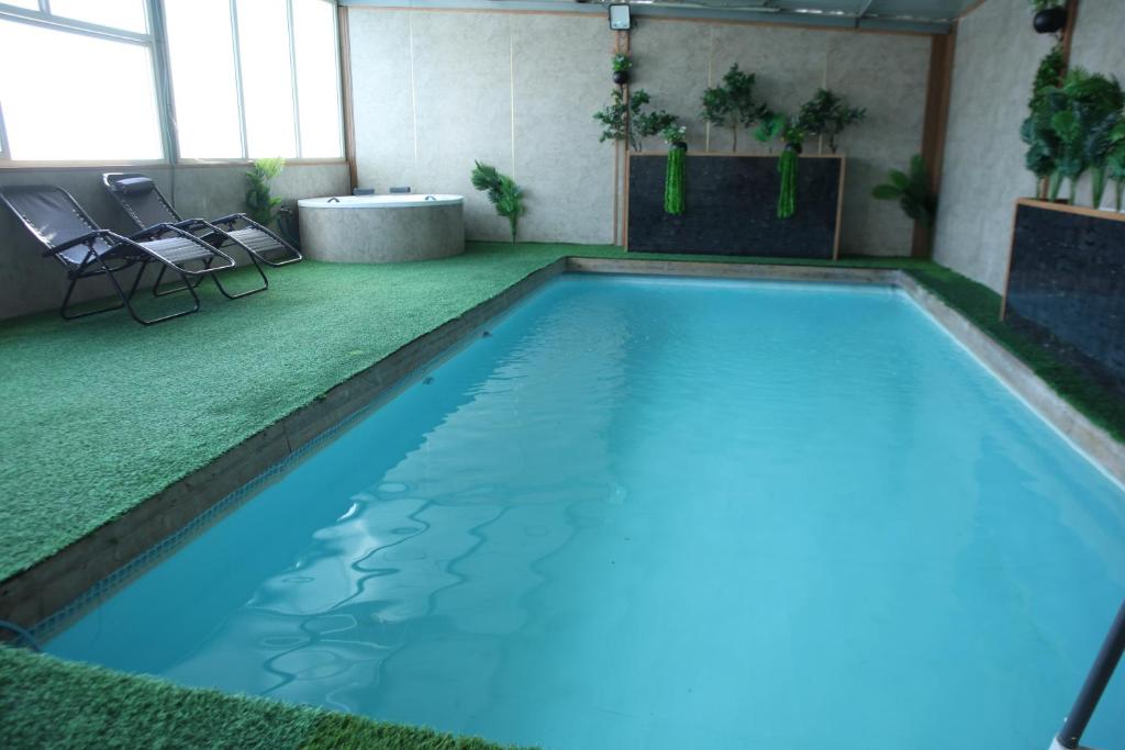 a swimming pool with blue water in a room at נוף הכפר - 6 חדרי אירוח לזוגות ומשפחות עם ג'קוזי ובריכה מחוממת משותפים במתחם in Buq‘ātā