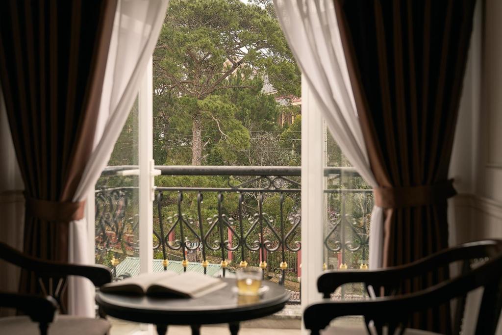 a table and chairs in front of a window at Hill Side Town Hotel DaLat in Da Lat