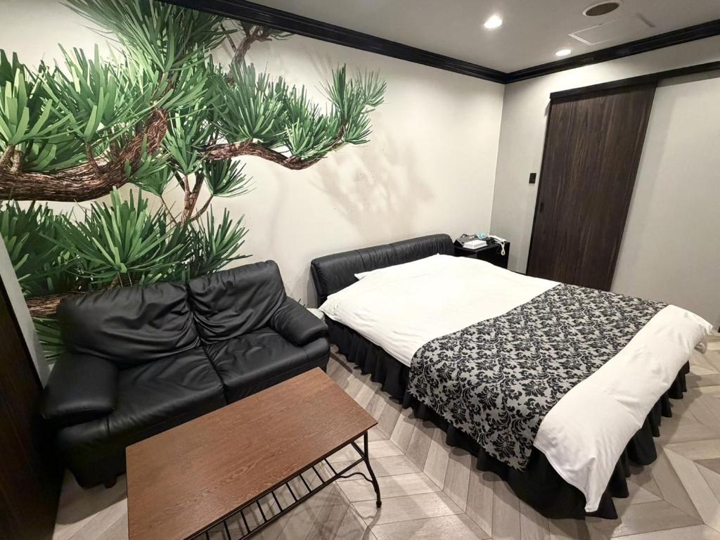 a bedroom with a bed and a leather chair at Carnet (Adult Only) in Amagasaki