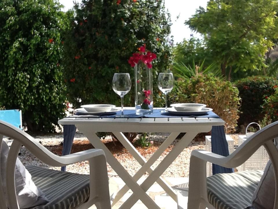 una mesa blanca con 2 sillas y 2 copas de vino en Pissouri Beach House - Image en Pissouri