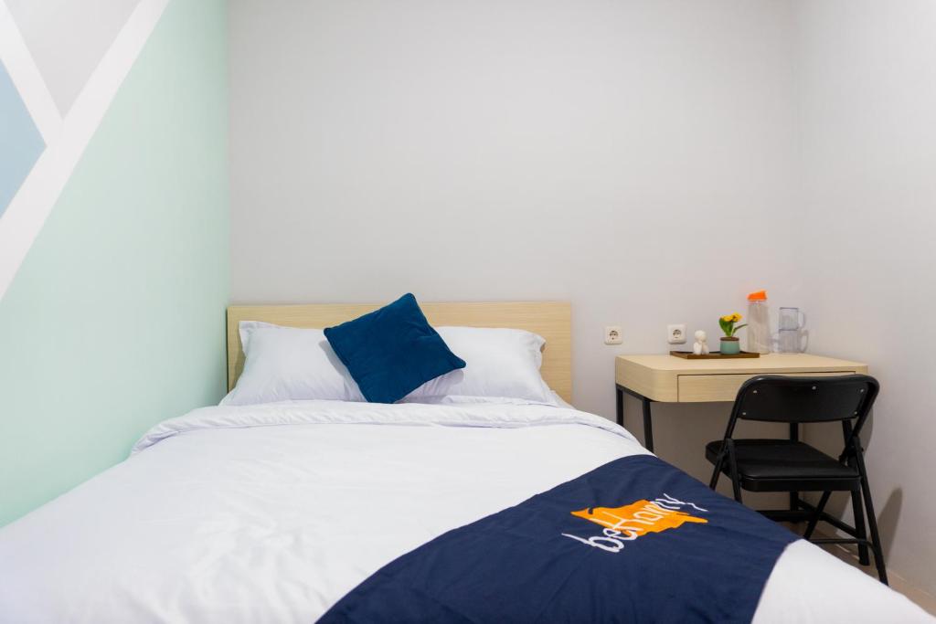 a bedroom with a bed and a desk with a chair at Behomy Suhat Malang in Karangjepun
