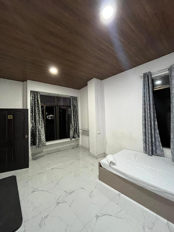 a large room with a bed and two windows at Aizawl View Hotel in Āīzawl
