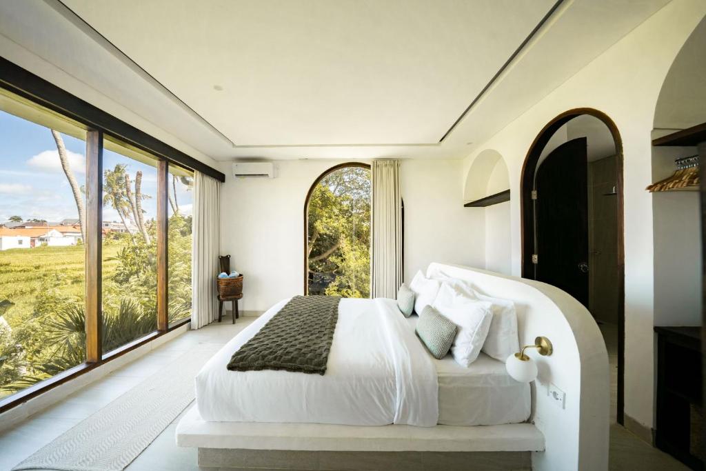a bedroom with a large white bed and large windows at Didi Apartment Seseh in Munggu