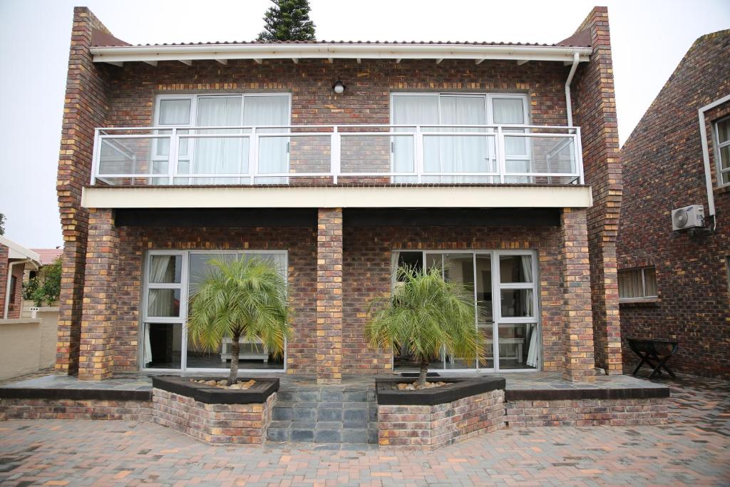 a brick building with two palm trees in front of it at Twin Okes in Jeffreys Bay