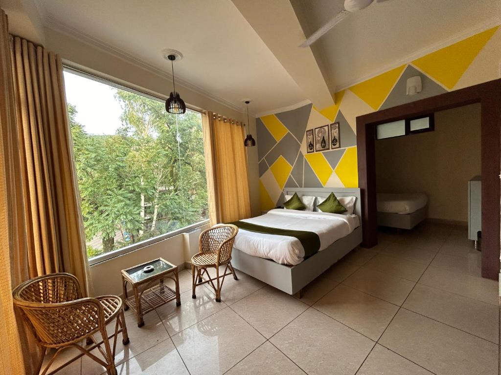 a bedroom with a bed and a large window at Hotel Clover Inn malsi in Dehradun