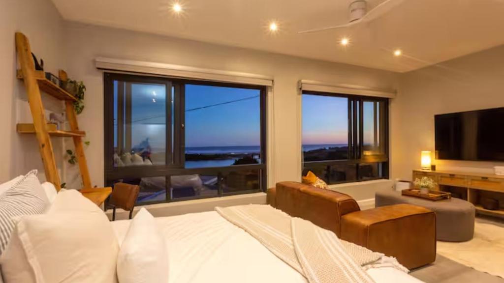 a living room with a bed and a large window at Blue Bay Studio Apartment in Wilderness
