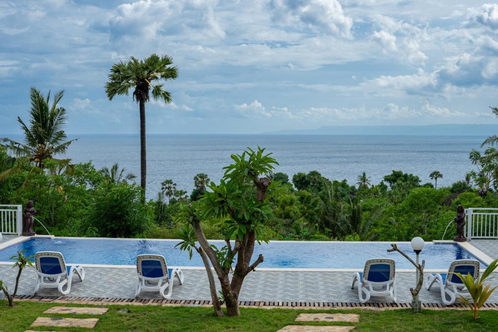 a pool with chairs and a view of the ocean at Gistari Inn & Restaurant in Seraya