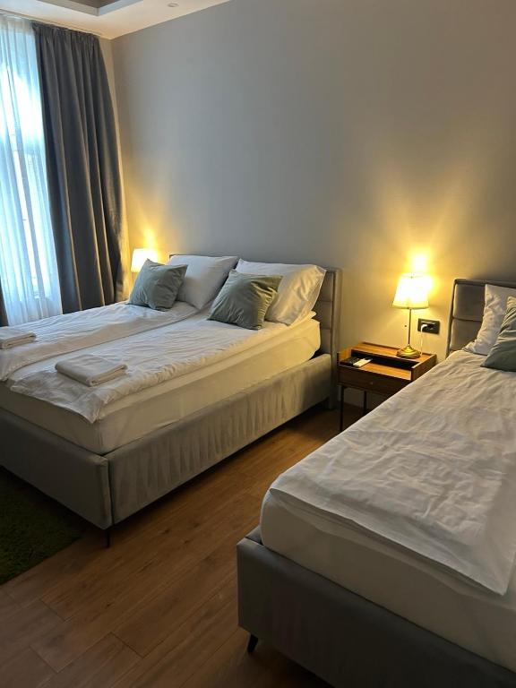 two beds in a hotel room with two lamps at Hotel Nacional in Bosanska Gradiška