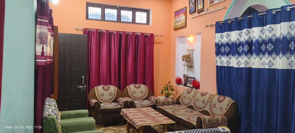 a living room with chairs and a table and red curtains at Green Valley Homestay in Barkot