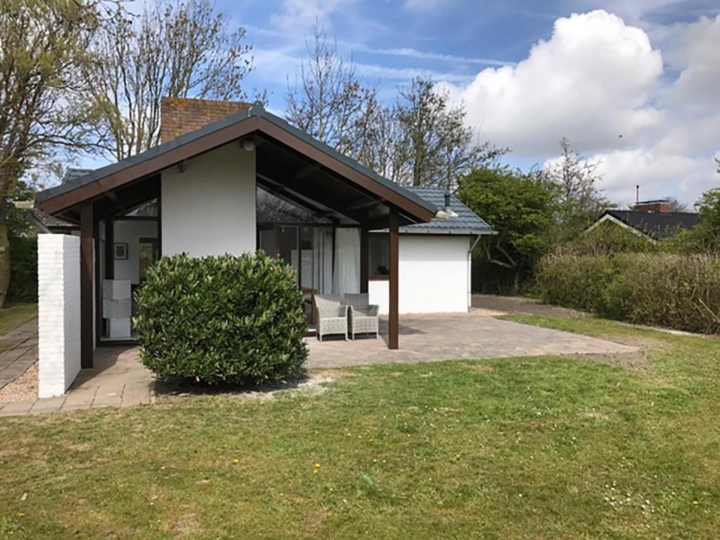 a small white house with a black roof at Spacious 6p vacation home with garden in Zoutelande