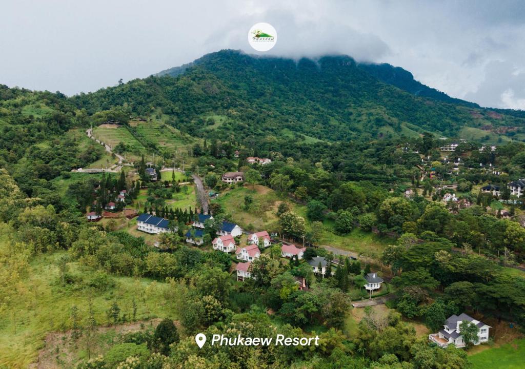 a hot air balloon flying over a village on a hill at Phukaew Resort & Adventure Park in Khao Kho