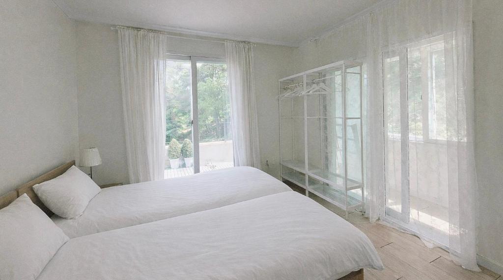 a white bedroom with two beds and a window at 대전 SJ Haus in Daejeon