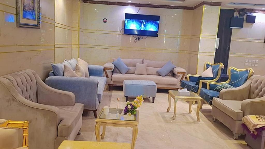 a living room with couches and a tv on a wall at ابراج الجود للشقق المخدومة in Al Ḩawīyah