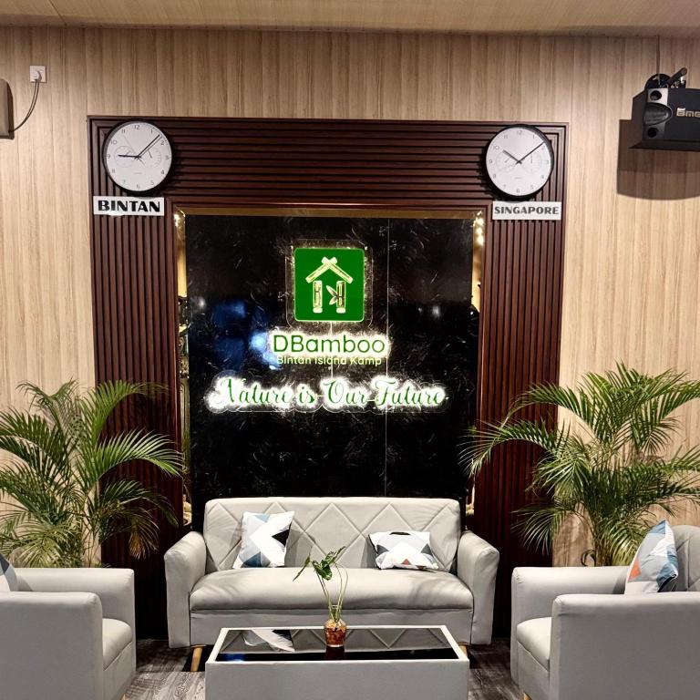 a lobby with a couch and clocks on the wall at "D'BAMBOO KAMP" Desa Wisata Ekang in Lagoi