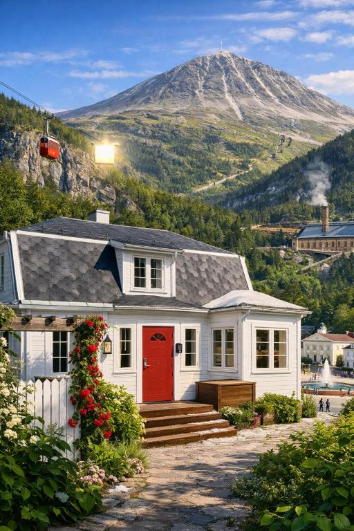 a white house with a red door and a mountain at Villa Rjukan in Rjukan