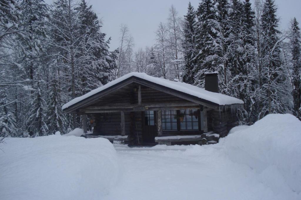 a cabin with snow on the roof in the woods at Toola-Lodge in Syöte