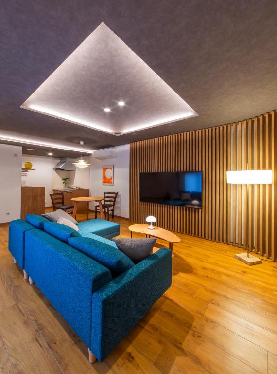 a living room with a blue couch and a television at MONTIS HOTEL Hida Takayama in Takayama