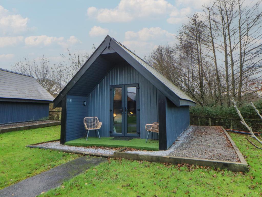a blue shed with two chairs in a yard at Glamping Tri Pod 2 - Gower in Swansea