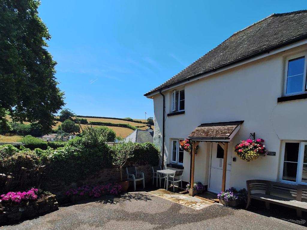 a white house with a bench and a table at Orchard Cottage in Dawlish