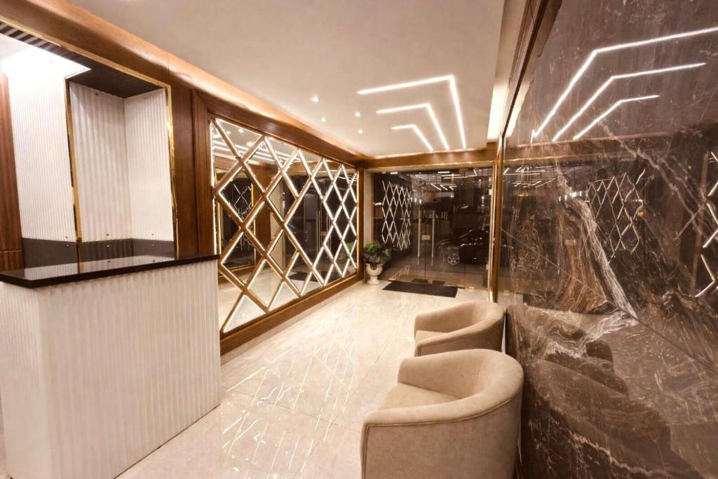 eine Lobby mit zwei Stühlen und einer Glaswand in der Unterkunft Sama AL Hamra Hotel Apartments in Raʼs Bayrūt
