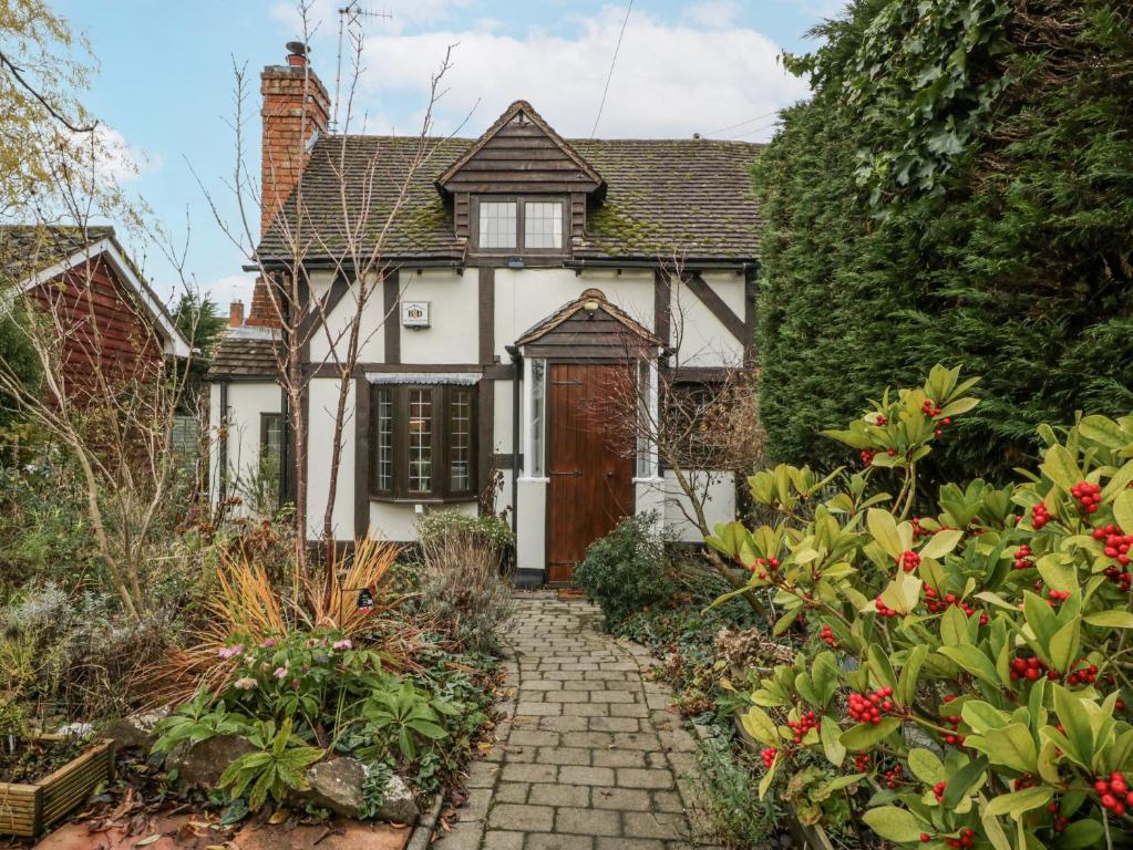 a white house with a brown door and some flowers at Magpie Cottage in Worcester