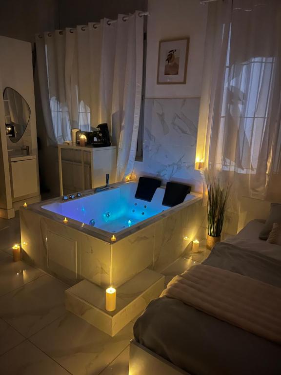 a room with a tub with lights in a bedroom at Love White Room Privée avec Spa privatif in Tourcoing