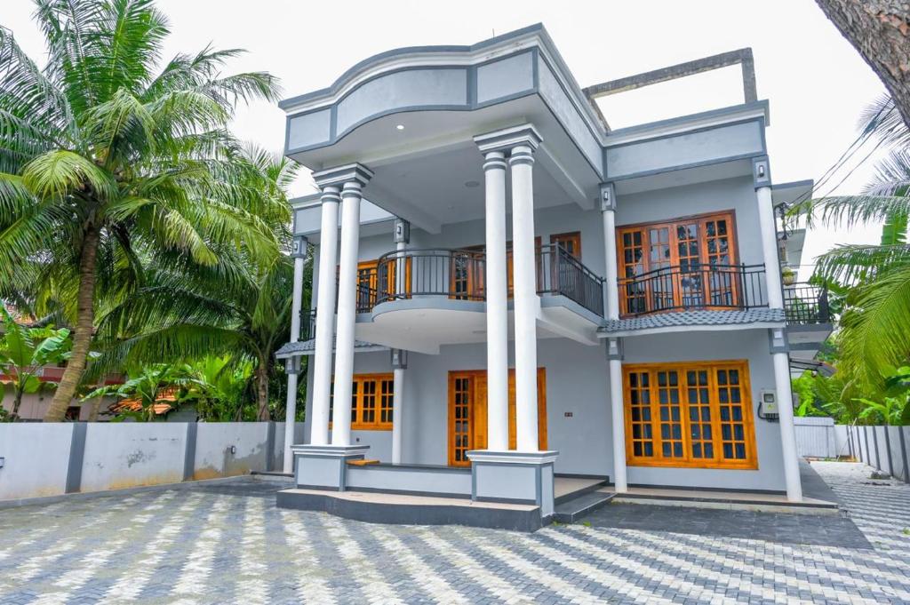 a white house with orange doors and palm trees at Rika Guest House in Kokkuvil East