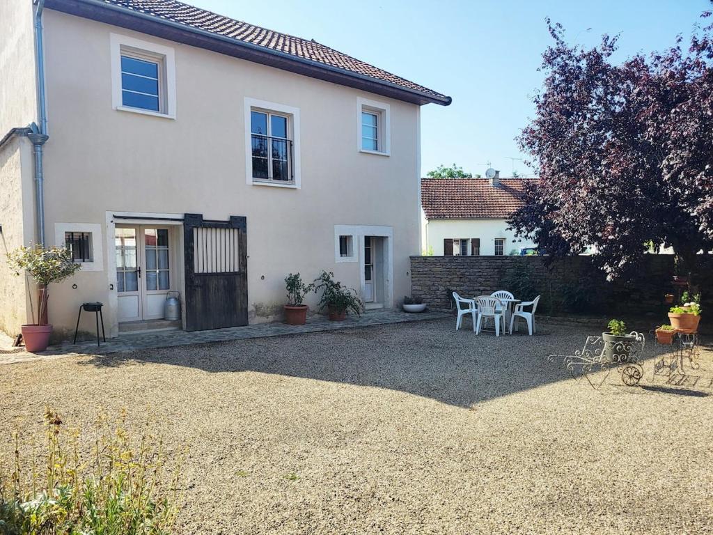 a white house with a table and chairs in a yard at L'Etalon, maison dans corps de ferme in Chailly-sur-Armançon