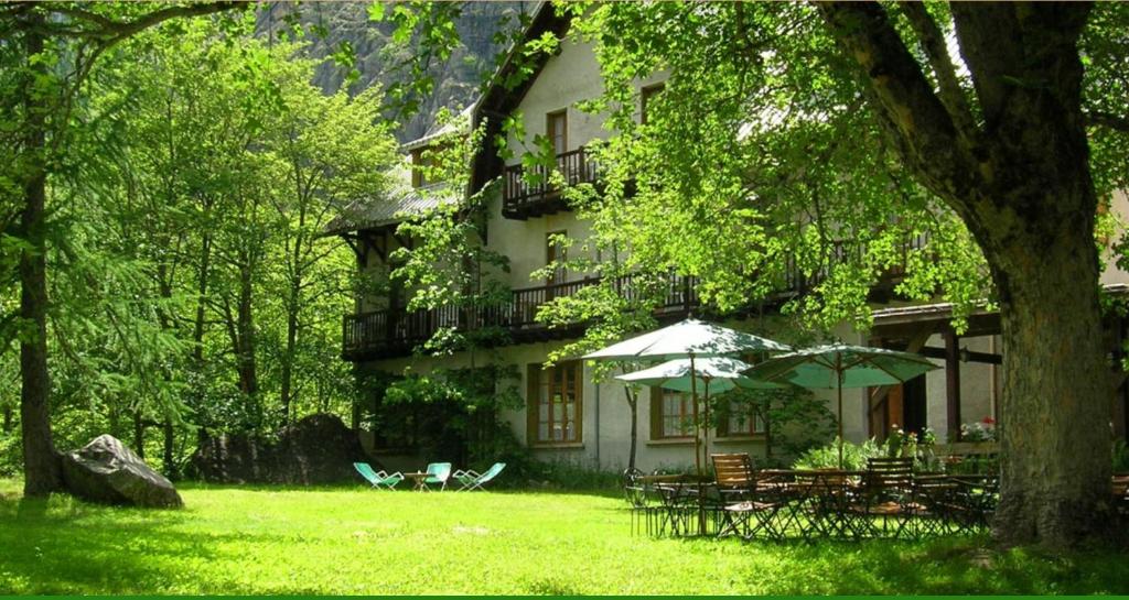a building with tables and umbrellas in front of it at Chalet Hotel d Ailefroide in Ailefroide