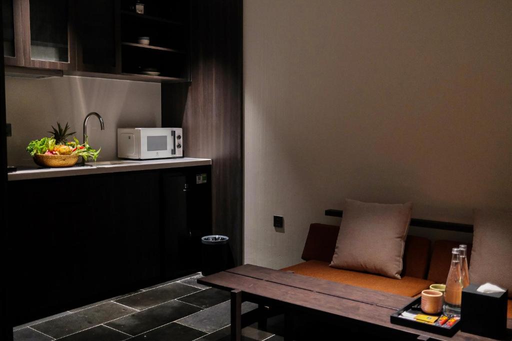 A compact sitting and kitchenette area with a microwave, sink, bench and low table.
