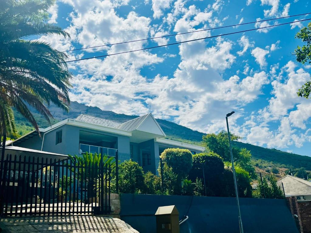 a blue house with a fence and a palm tree at Paarl View House in Paarl