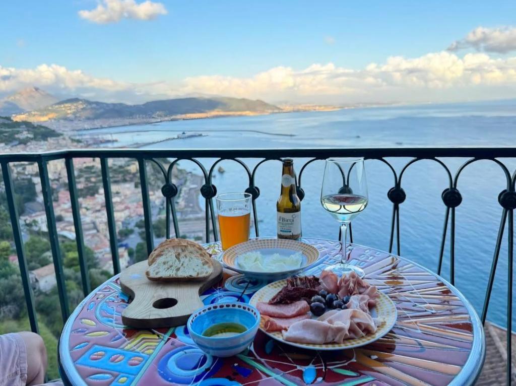 a table with food and a glass of wine on a balcony at Casa Beatrice Amalfi Coast in Vietri sul Mare