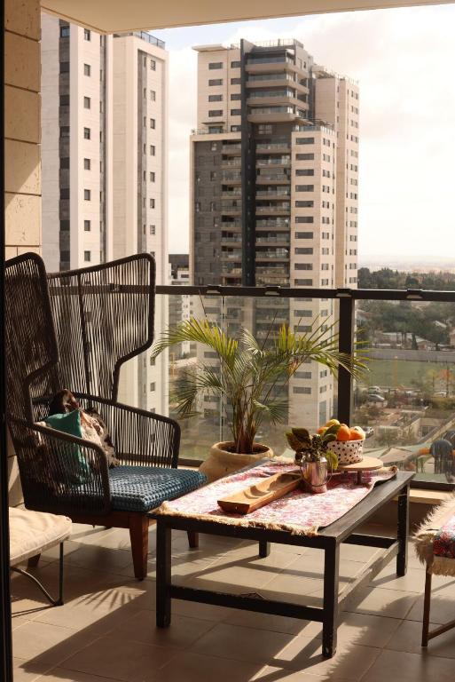 a balcony with a table and chairs and a view of a city at שלוות העמק - דירת 3 חדרי שינה במיקום מרכזי in Ganne Tiqwa