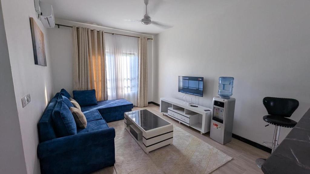a living room with a blue couch and a tv at 1brm,2bdrm,3bdrm Palm Ridge Heavens Vipingo in Kilifi