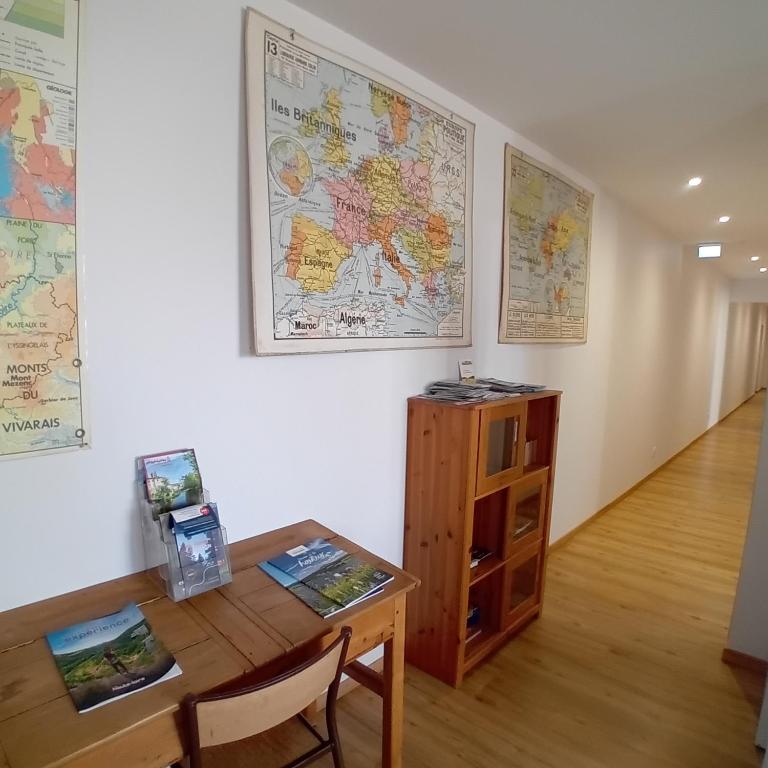 a room with a desk and a table and a map on the wall at Gîte et Chambres d'hôtes du Musée Ecole in Le Monastier sur Gazeille