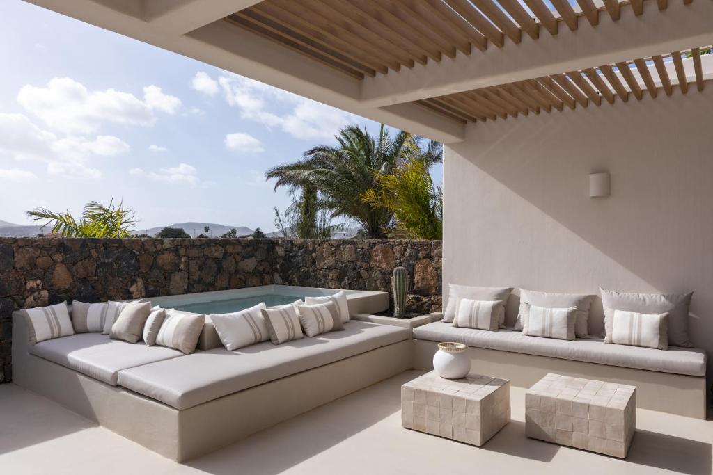 a patio with a couch and a hot tub at Gara Suite Boutique Design Villa Private Pool in Lajares