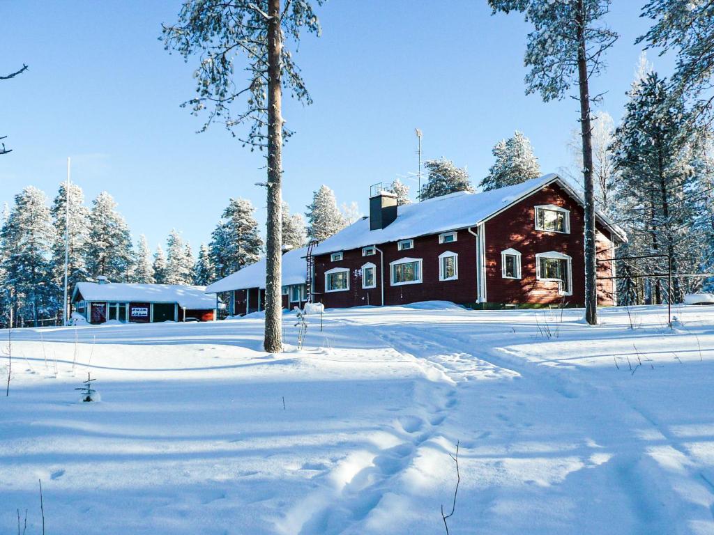 a red house in the snow with trees in front at Kätkävaara Wilderness Lodge in Muurola