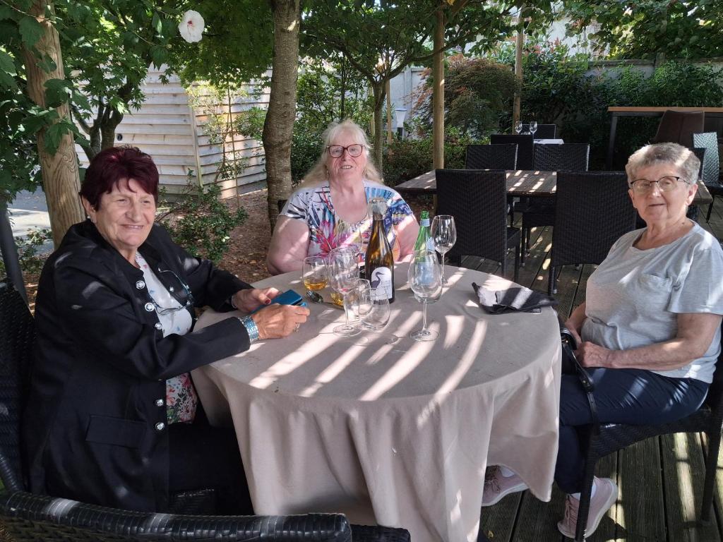camping car في Saint-Georges-du-Bois: ثلاث نساء مسنات يجلسن على طاولة مع كؤوس نبيذ