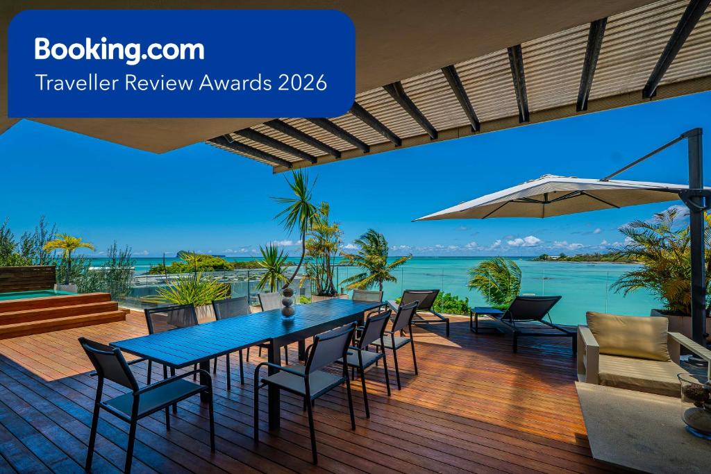 a table and chairs on a deck with a view of the ocean at Penthouse 3 chambres Vue Lagon imprenable in Calodyne