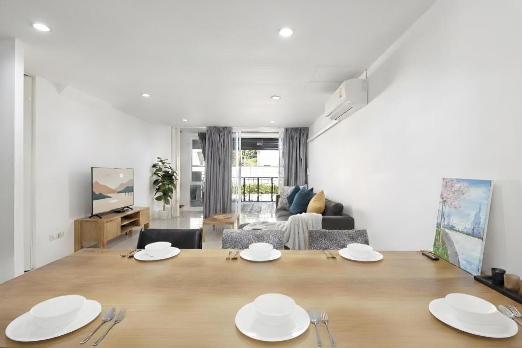 a living room with a large wooden table with plates on it at Spacious 3BR BKK NEAR 3 Private Bathrooms FAMILY STAY in Min Buri